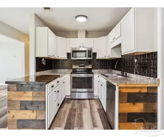 a kitchen with granite countertop a stove top oven and cabinets