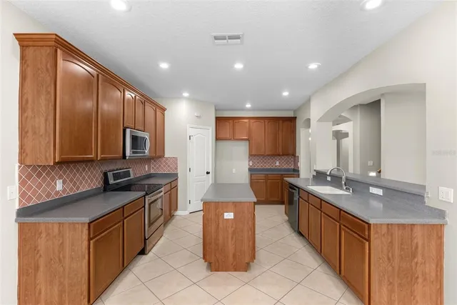 a kitchen with stainless steel appliances granite countertop a stove a sink and a refrigerator