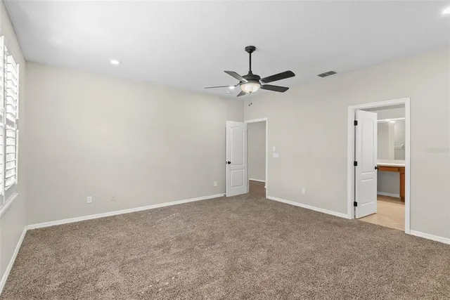 an empty room with a chandelier fan and windows