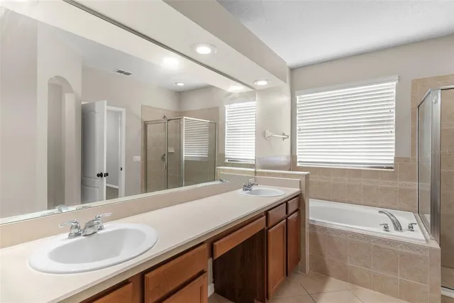 a bathroom with a sink double vanity granite tub shower and a mirror