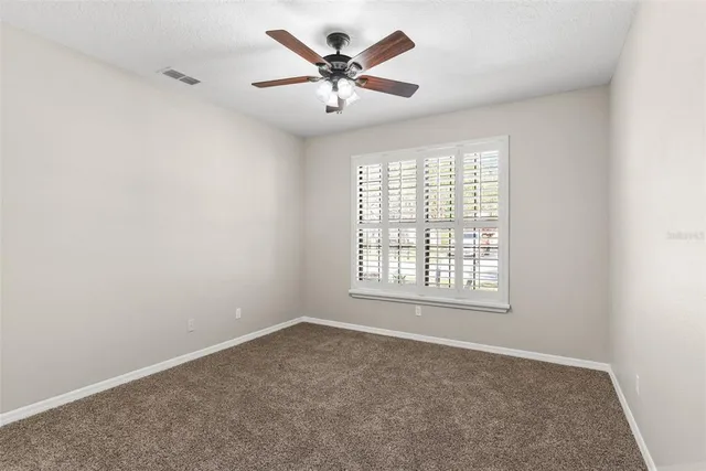 an empty room with windows and a ceiling fan