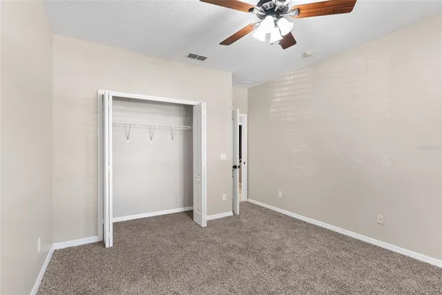 an empty room with a ceiling fan and carpet