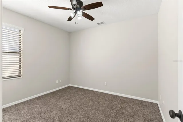an empty room with a window and a fan