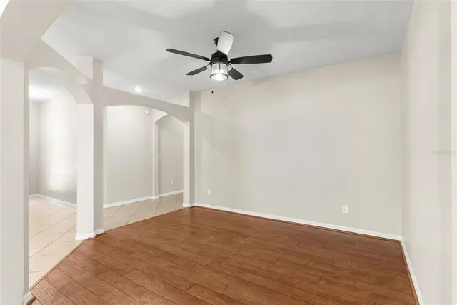 an empty room with wooden floor fan and windows