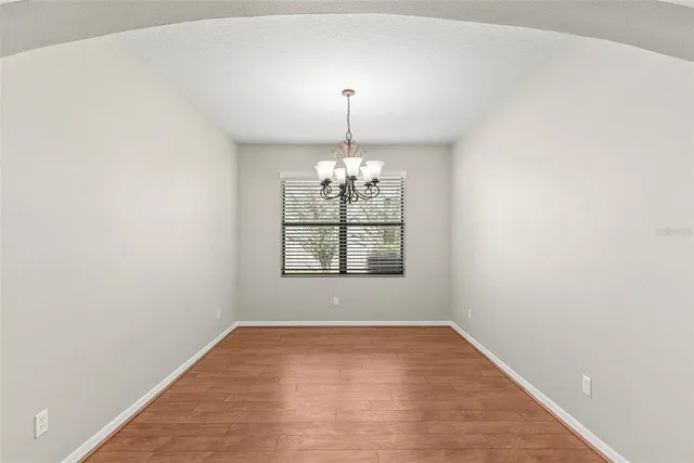 an empty room with chandelier fan and windows