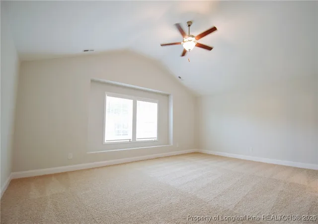 an empty room with ceiling fan and windows