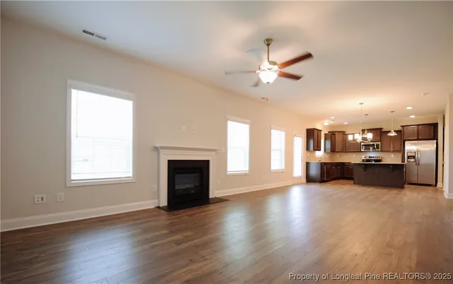an empty room with kitchen view and a fireplace