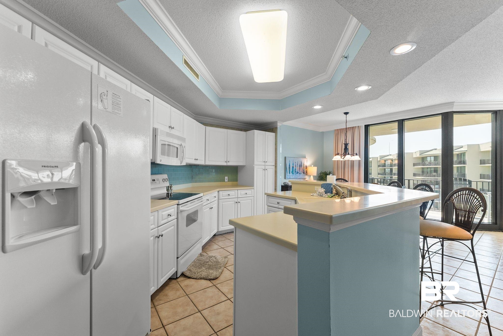 27580 Canal Road, Unit 1427 Orange Beach, AL 36561 - Photo 9 of 38 Kitchen featuring white appliances, crown molding, a textured ceiling, light countertops, and white cabinetry