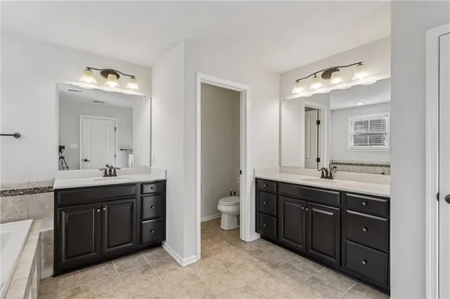 a bathroom with a double vanity sink and mirror with toilet