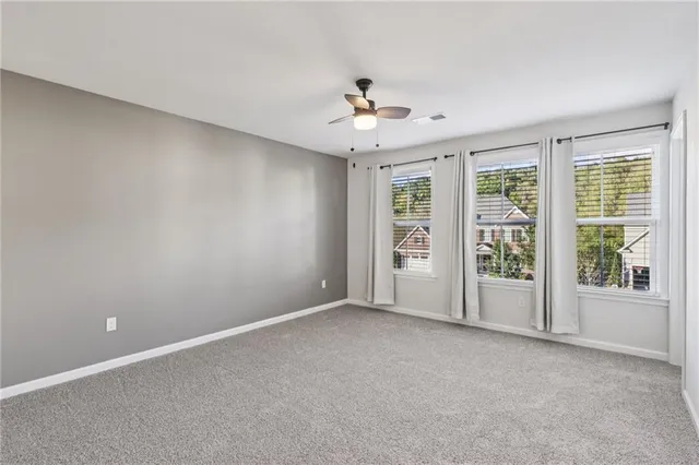 an empty room with chandelier fan and windows