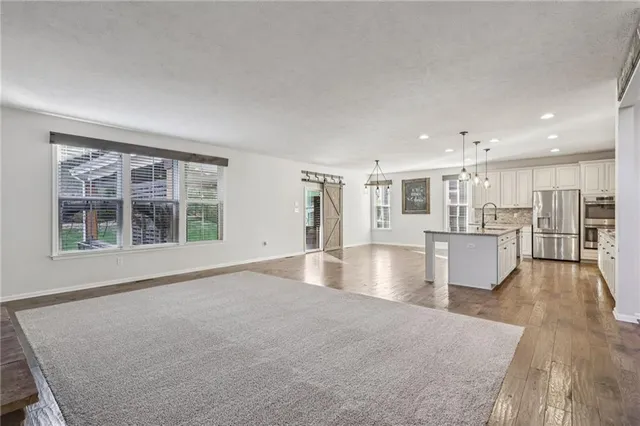a view of an empty room with kitchen view and a window