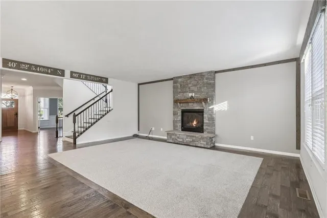 a view of an empty room with wooden floor and a fireplace