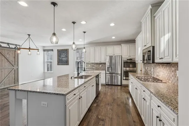 a large kitchen with stainless steel appliances kitchen island granite countertop a sink stove and refrigerator