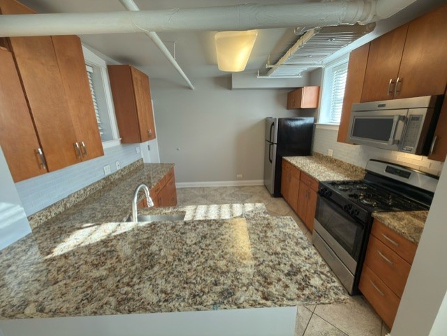 2147 West Lunt Avenue, Unit G Chicago, IL 60645 - Photo 4 of 16 a kitchen with kitchen island granite countertop a sink stove and cabinets