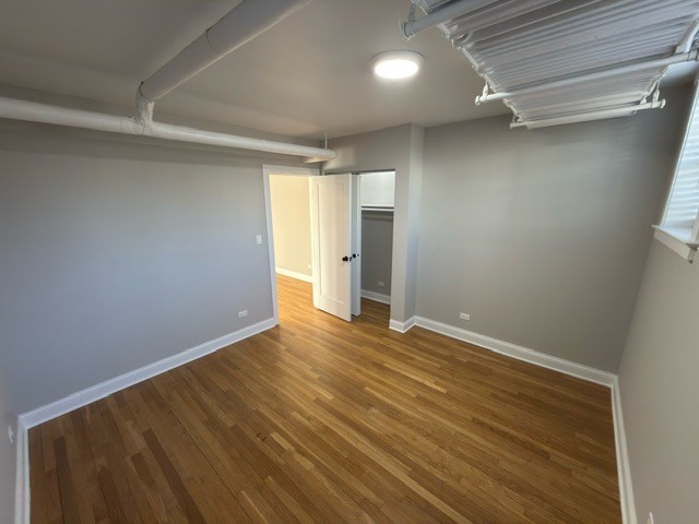 2147 West Lunt Avenue, Unit G Chicago, IL 60645 - Photo 9 of 16 a view of an empty room with wooden floor and a window