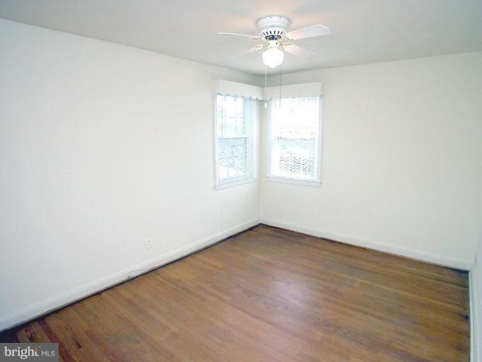 213 Blenheim Road Baltimore, MD 21212 - Photo 8 of 16 an empty room with wooden floor ceiling fan and windows