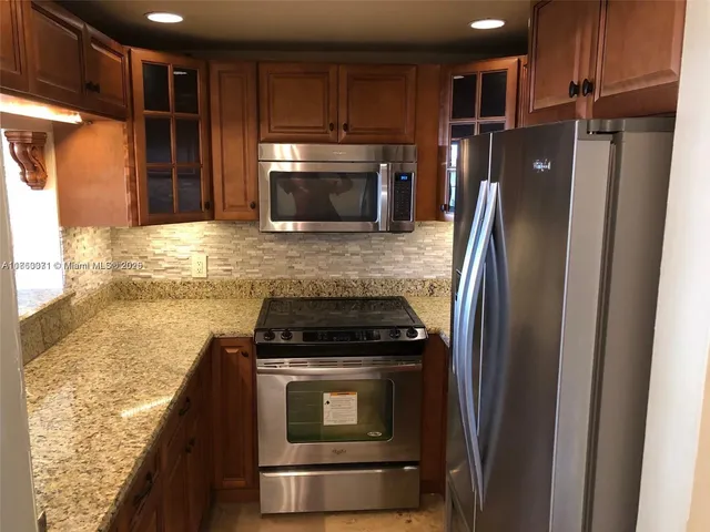 a kitchen with granite countertop a refrigerator stove and microwave