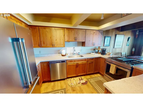 a kitchen with stainless steel appliances kitchen island granite countertop a sink refrigerator and cabinets