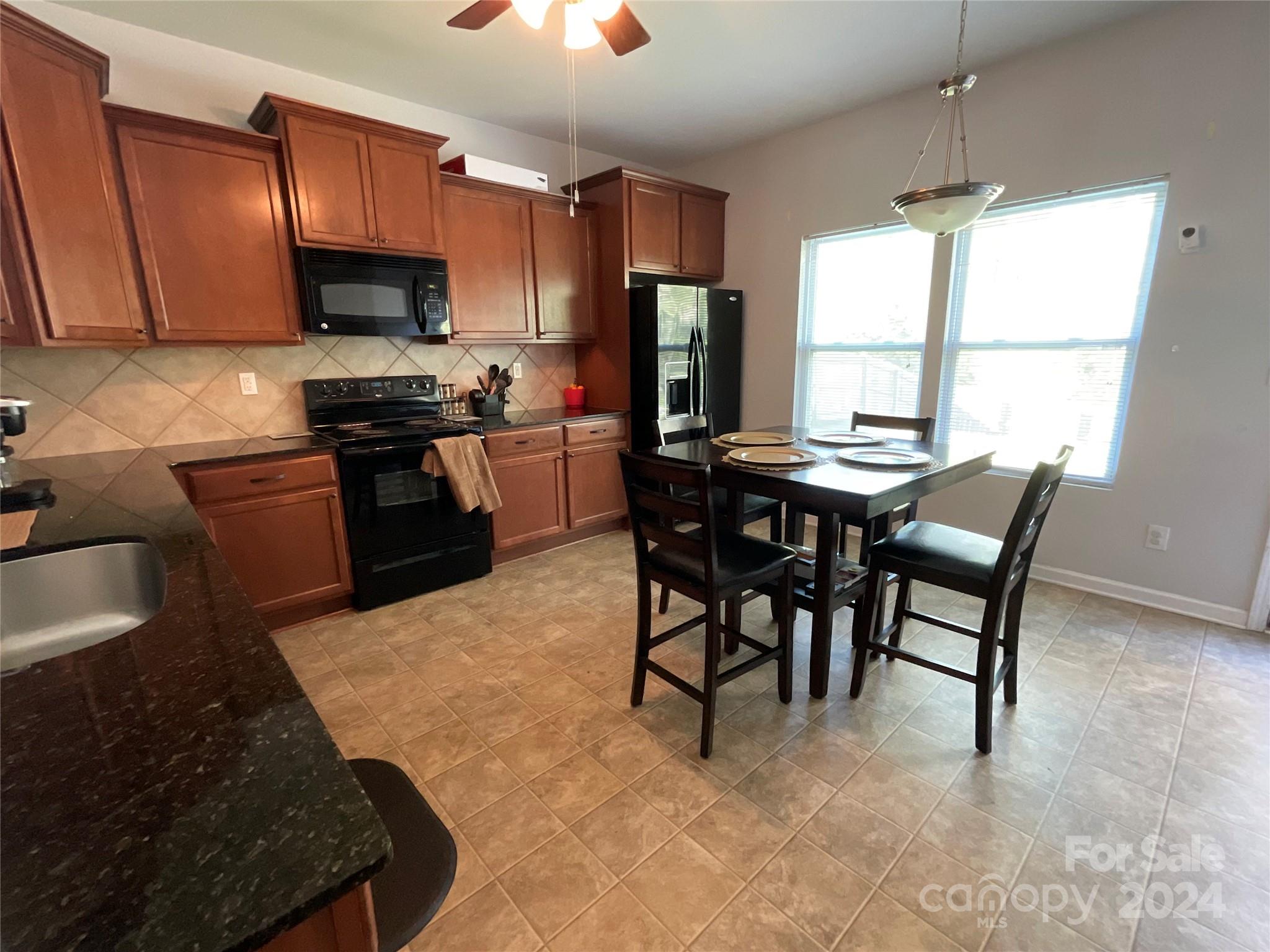3271 Brickwood Circle Midland, NC 28107 - Photo 6 of 20 a kitchen with granite countertop a stove a sink a dining table and chairs