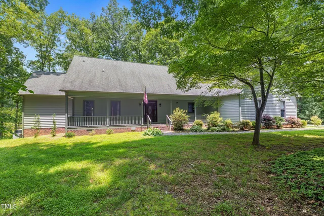 a front view of a house with a garden and trees