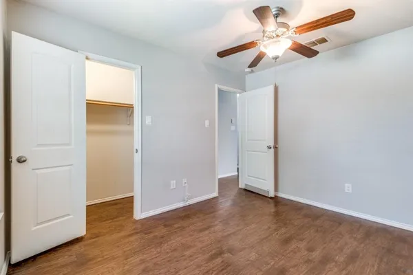 an empty room with wooden floor fan and windows