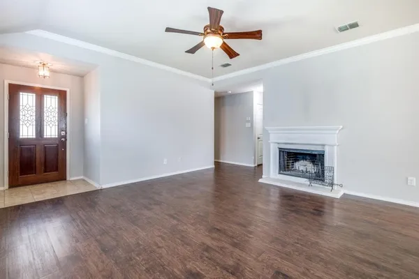 a view of an empty room with wooden floor a fireplace and a window