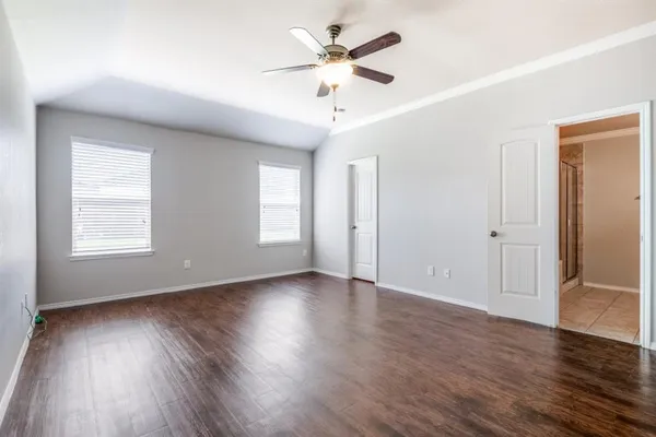 an empty room with wooden floor chandelier fan and windows