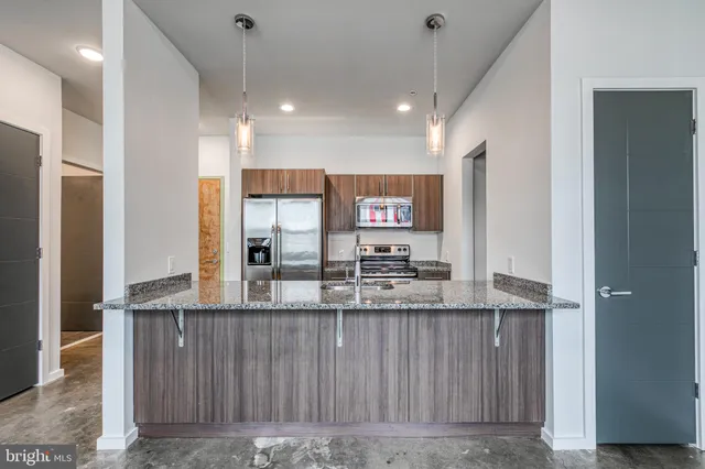 a kitchen with kitchen island granite countertop a sink and refrigerator