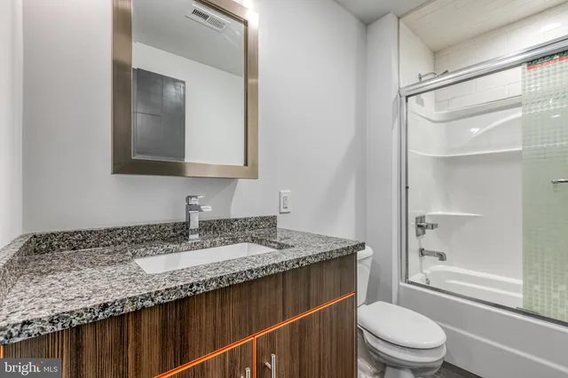 a bathroom with a granite countertop sink toilet and shower