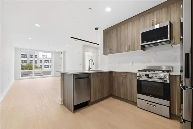 a kitchen with stainless steel appliances a stove a microwave and white cabinets