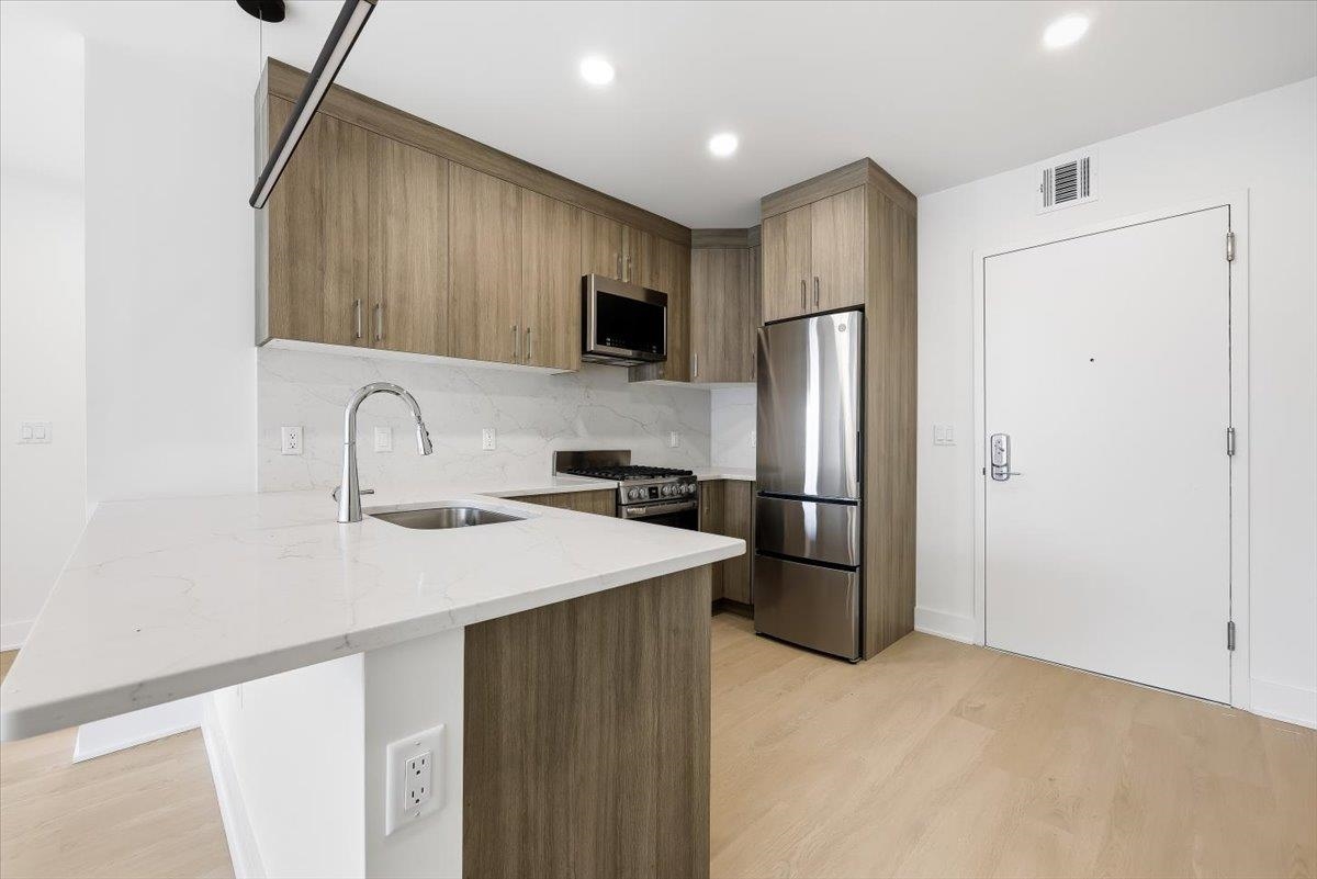 303 Madison Street, Unit 406 Hoboken, NJ 07030 - Photo 3 of 29 a kitchen with stainless steel appliances a refrigerator and a sink