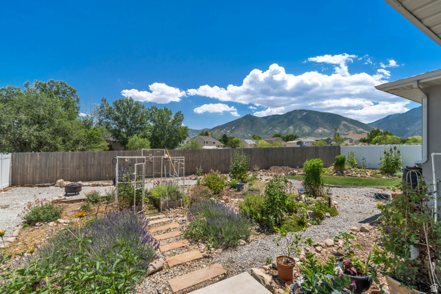 683 Kings Landing Tooele, UT 84074 - Photo 38 of 39 Landscaped backyard featuring gravel pathways, a variety of plantings, and a wood privacy fence