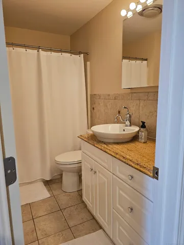 a bathroom with a granite countertop sink a toilet and a mirror