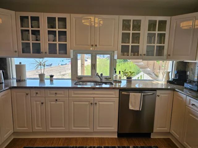 a kitchen with stainless steel appliances granite countertop a sink and cabinets with wooden floor