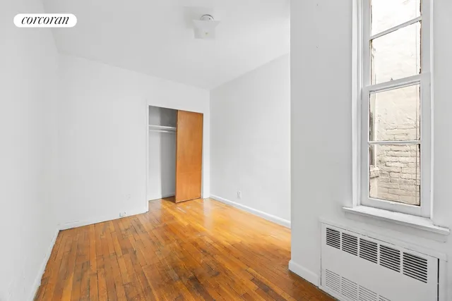 a view of an empty room with a window and wooden floor