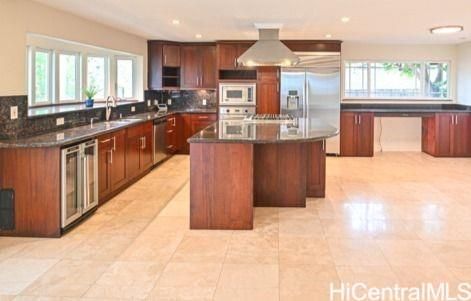 a large kitchen with kitchen island a sink a counter top space a large window and stainless steel appliances