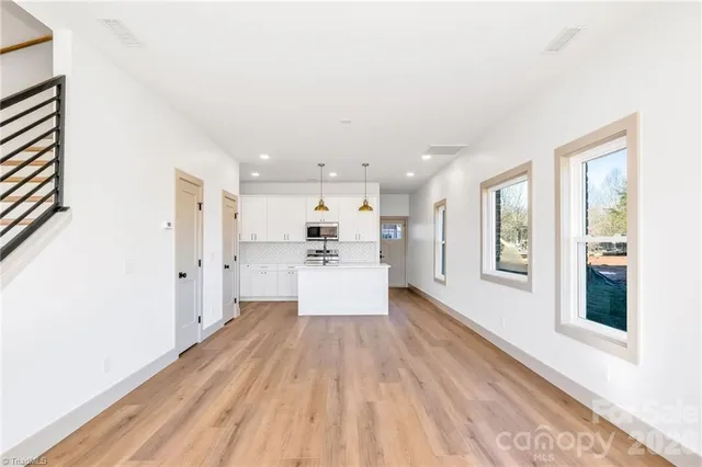 a large white kitchen with stainless steel appliances kitchen island a large counter top and a refrigerator