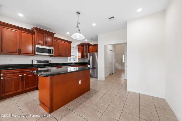 a large kitchen with granite countertop a stove a sink dishwasher and a microwave oven with white cabinets