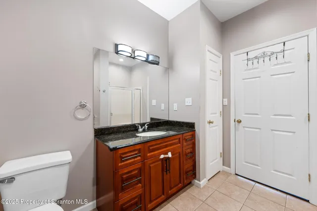 a bathroom with a granite countertop toilet sink and mirror