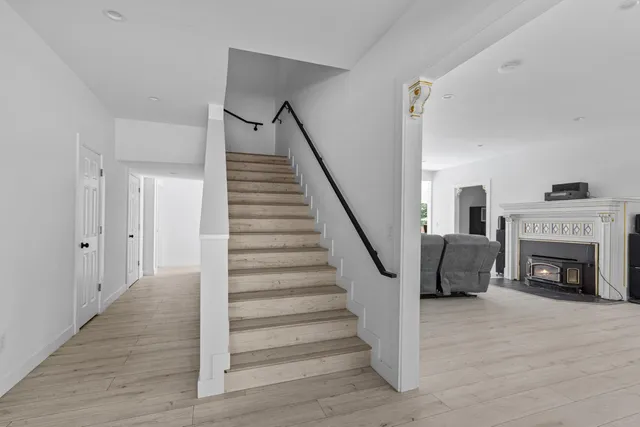 a view of an empty room with wooden floor fireplace and a window
