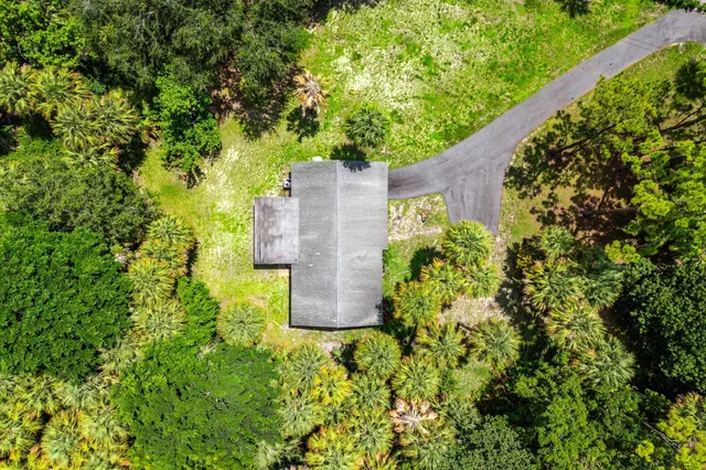 an aerial view of a house with a yard and large trees