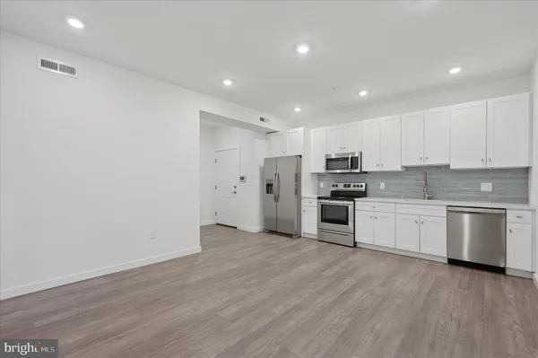 a kitchen with stainless steel appliances a refrigerator sink and white cabinets