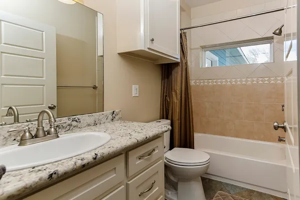 a bathroom with a granite countertop sink toilet and shower