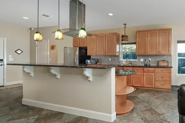 a kitchen with stainless steel appliances granite countertop a sink a stove a counter space and cabinets