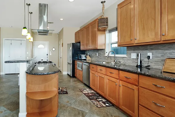 a kitchen with stainless steel appliances granite countertop a sink a stove and a cabinets
