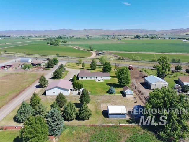 1095 County Road 70 Weiser, ID 83672 - Photo 4 of 44 Expansive property featuring a single-story residence with a brown roof, multiple outbuildings including a large metal-sided structure with a light-colored roof, and a second metal-sided building with a white roof