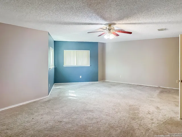en empty room with windows and ceiling fan
