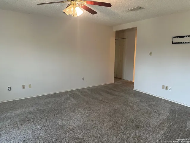 an empty room with a ceiling fan and window