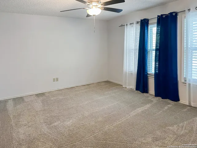 an empty room with windows and fan