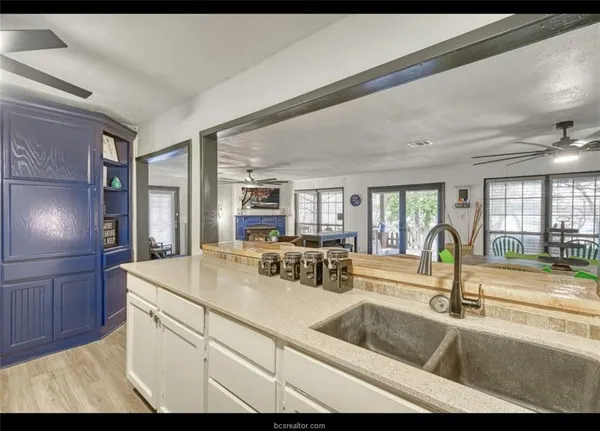 a kitchen with a sink dishwasher stove and white cabinets with wooden floor